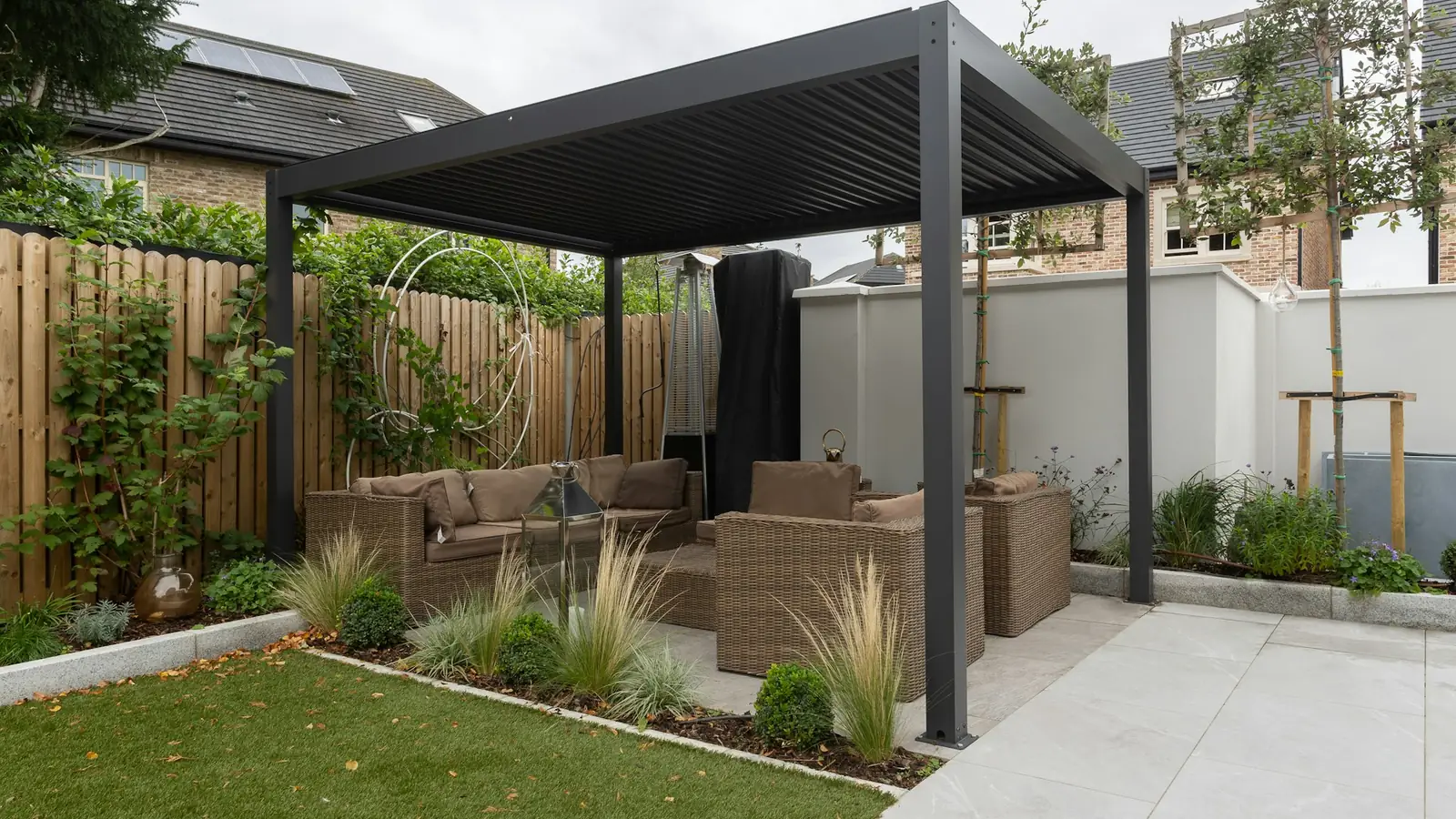 Pergola à lames orientables anthracite au-dessus d’un salon de jardin